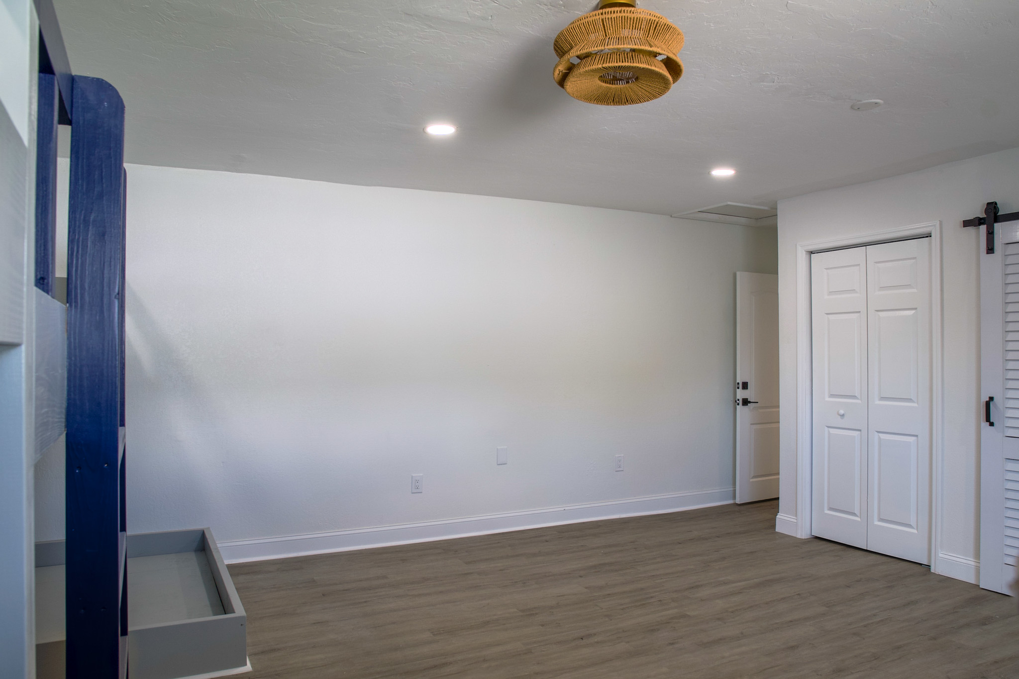 Renovated short-term rental bedroom in Tampa, FL with gray wood-look vinyl plank flooring, a custom built-in bunk bed, recessed lighting, and a barn-style closet door.